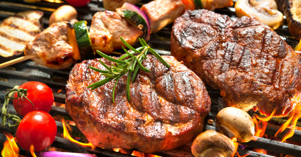 A képen szelet húsokat látunk grillen, mellette zöldségekkel